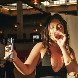 A woman taking a selfie, while tasting Three Spirit, in the sun 